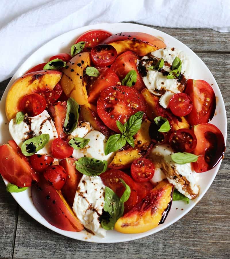 Grilled Peach Caprese ~ grilled sweet peaches, summer tomatoes, fresh mozzarella or burrata, salty prosciutto, basil and balsamic reduction.