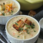 bowl of roasted cauliflower soup topped with croutons and cheddar cheese