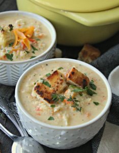 bowl of roasted cauliflower soup topped with croutons and cheddar cheese