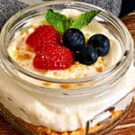 no bake cheesecake jars in mason jar topped with strawberries and blueberries.