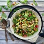 overhead view white bowl with Avocado Chickpea Tuna Salad garnished with small basil leaves.