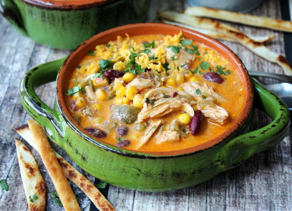 overhead view green bowl with slow cooker chicken enchilada soup garnished with cilantro