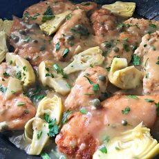 chicken piccata ~ overhead closeup of chicken in sauce with artichokes and capers