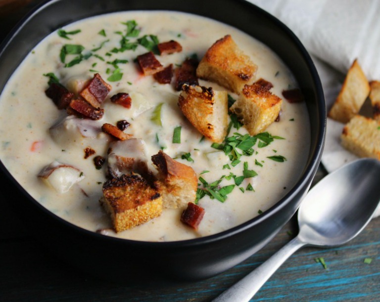black bowl filled with new england clam chowder topped with toasted croutons