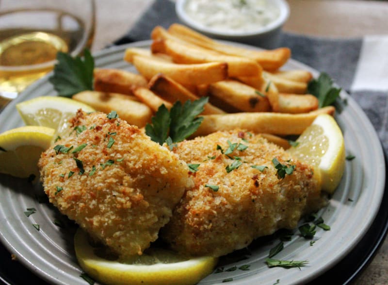 gray plate with crispy breaded cod, french fries and lemon wedges