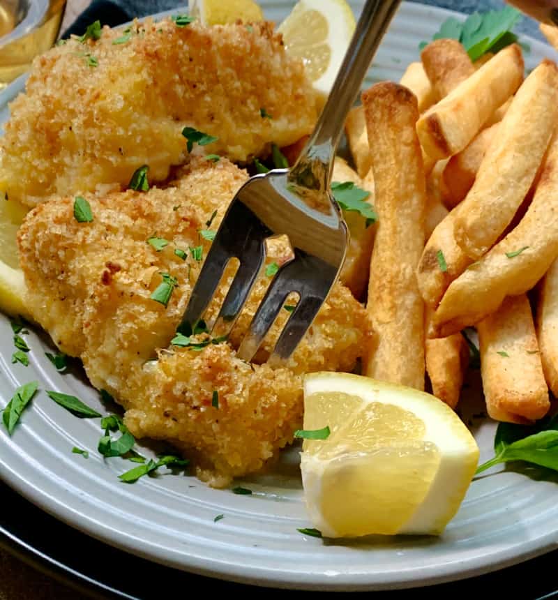 crispy baked cod on plate with fork piercing the fish