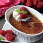 easy coffee creme brulee in white ramekin topped with a dollop of whipped cream and raspberries.