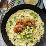 overhead view - black bowl with sweet corn risotto and grilled shrimp