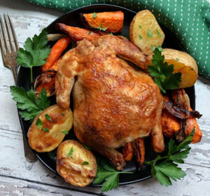 overhead view air fryer cornish hens with roasted potatoes and carrots