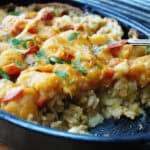 black casserole dish with cowboy tater tot casserole and serving spoon