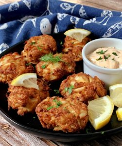 black plate with mini crab cakes and dipping sauce