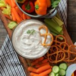 overhead view bowl of dill dip surrounded by bright colored chopped vegetables