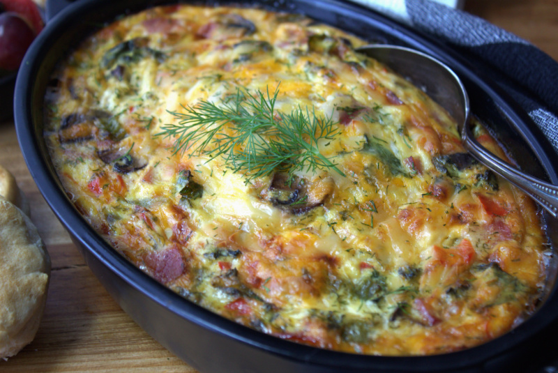 black casserole dish with scambled egg casserole garnished with fresh dill