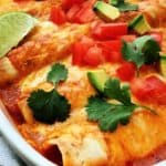 closeup of baked enchiladas in casserole dish topped with melted cheese
