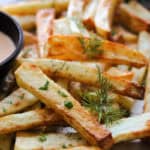 parchment paper with pile of air fryer french fries and dipping sauces