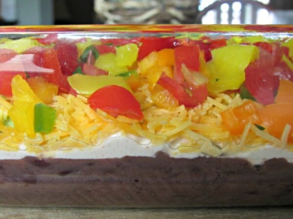 Layered Taco Dip: WARNING: it's too good to stop eating. Refried beans, spicy Greek yogurt, avocado, cheese, peppers. Just add tortilla chips.