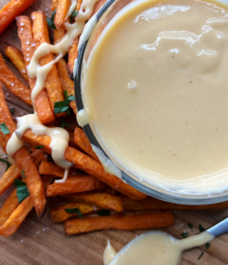 bowl of flourless cheese sauce surrounded by sweet potato fries