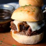 slow cooker french dip slider with bowl of au jus for dipping