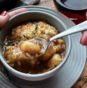 bowl of french onion gnocchi soup with spoonful lifted