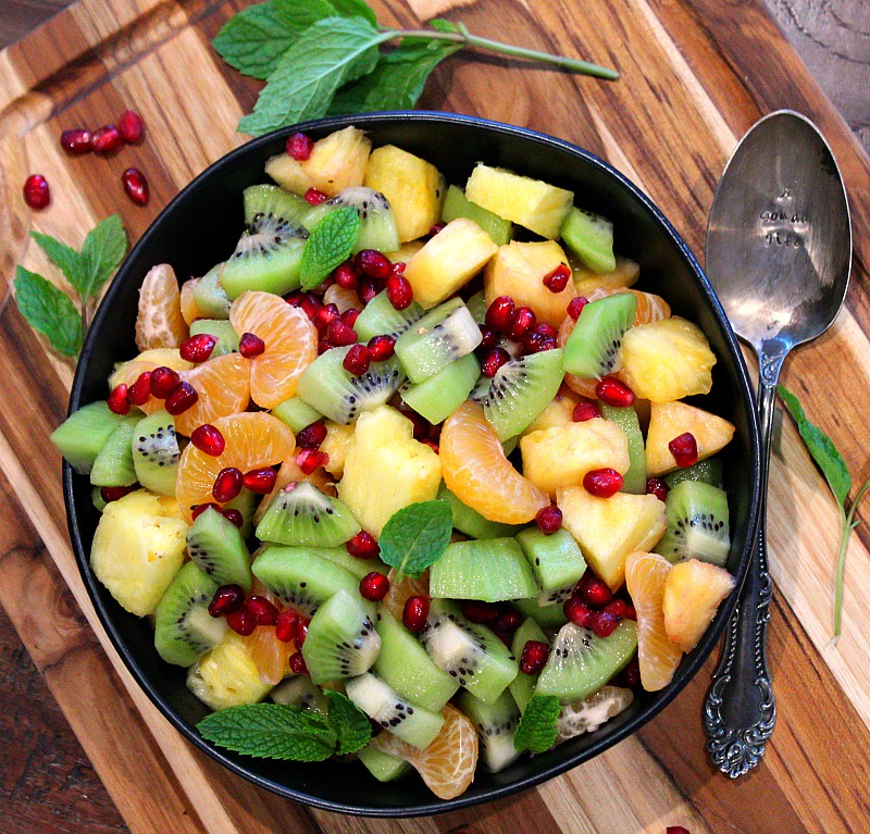 black bowl with salad of kiwi, mandarins, pineapple and pomegranate