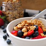 white bowl with yogurt topped with granola and fresh fruit