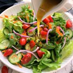 salad in white bowl with dressing poured over the top