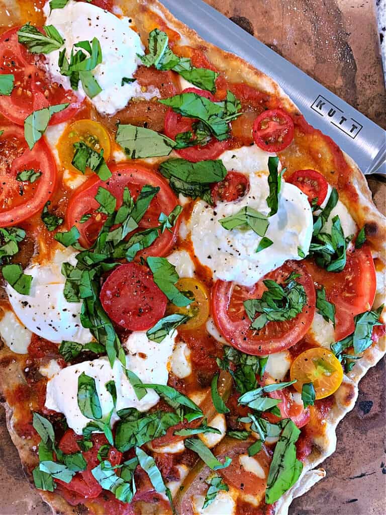 how to grill pizza closeup of margherita pizza garnished with basil