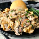 black plate with hamburger helper beef stroganoff, dinner roll and green beans