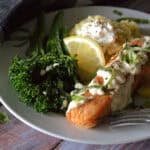 white plate with creamy honey mustard salmon garnished with lemon slice