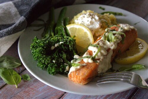 white plate with creamy honey mustard salmon garnished with lemon slice