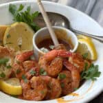 white bowl with hot honey butter old bay shrimp garnished with lemon slices