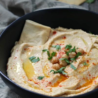 hummus in black bowl garnished with chick peas and olive oil