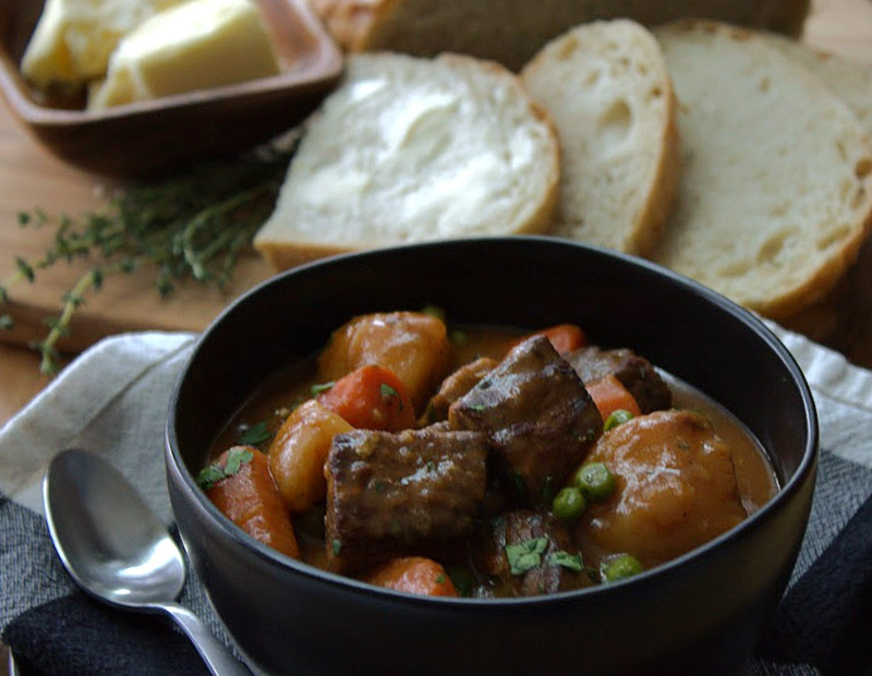 black bowl with irish guinness beef stew and slices of buttered bread