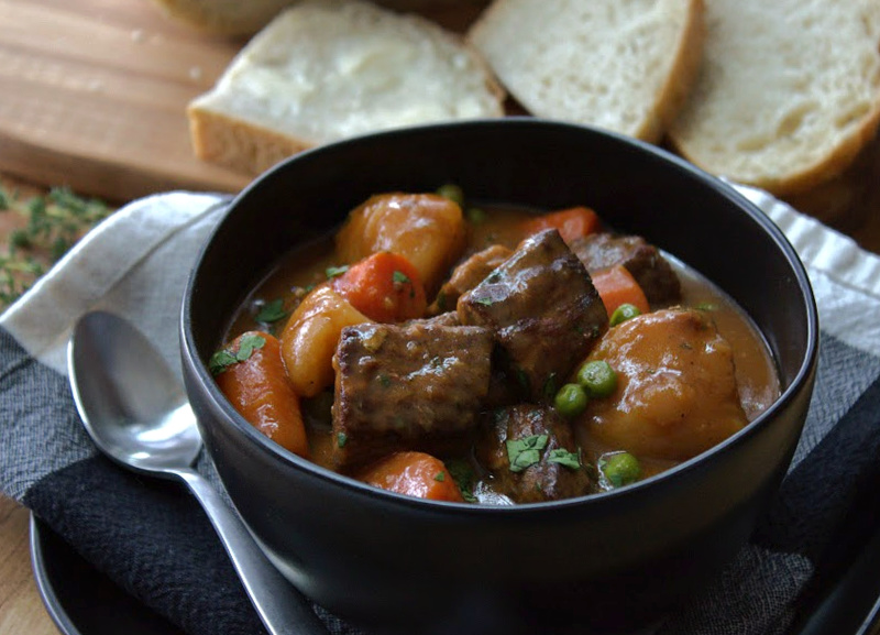 black bowl with irish guinness beef stew and sliced buttered bread