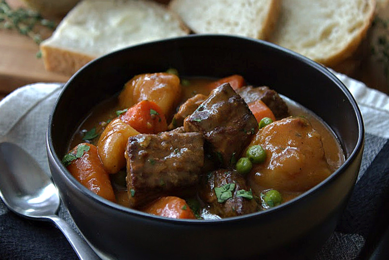 black bowl with irish guinness beef stew and slices of buttered bread