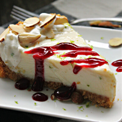 white plate with slice of authentic key lime pie drizzled with raspberry sauce