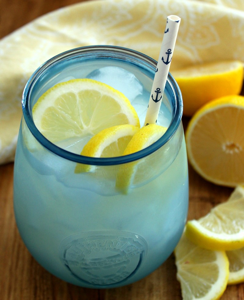 homemade lemonade in icy blue glass with sliced lemons