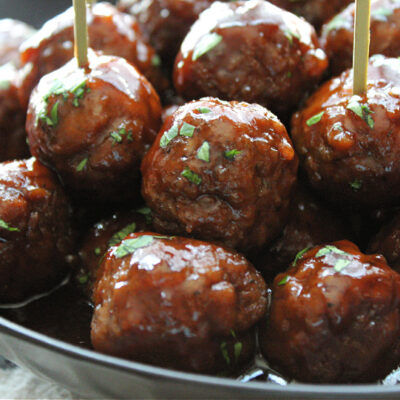 grape jelly meatballs recipe - black bowl filled with meatballs and sweet spicy sauce