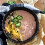 overhead view black bowl with mexicali dip garnished with sliced jalapenos