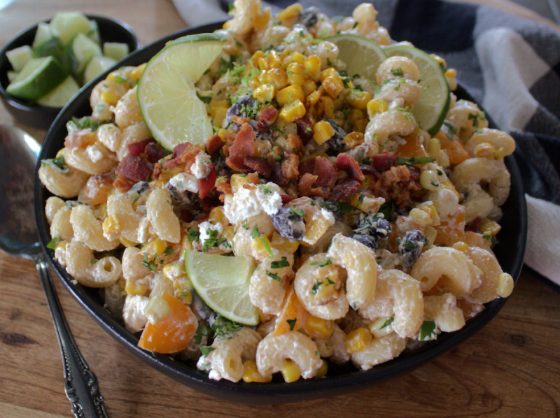 black bowl with mexican street corn pasta salad garnished with sliced lime