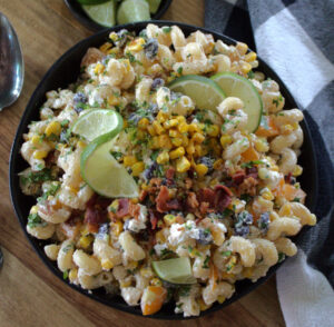 black bowl with mexican street corn pasta salad garnished with crispy bacon