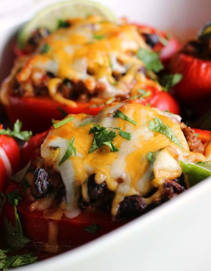 white casserole dish with mexican stuffed peppers baked in enchilada sauce
