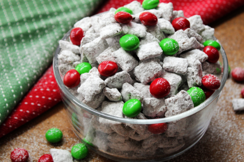 clear glass bowl with powdered sugar coated chex cereal with red and green M&M's