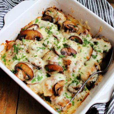 white baking dish with chicken breasts, melted mozzarella and golden mushrooms