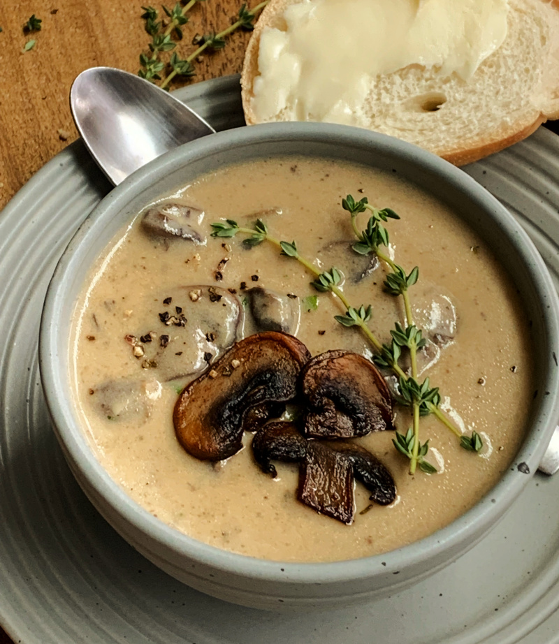 overhead view gray bowl with cream of mushroom soup garnished with sauteed mushroom and thyme sprigs