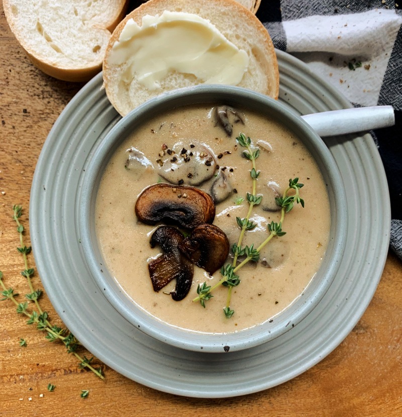 cream of mushroom soup garnished with sliced mushrooms and thyme sprigs