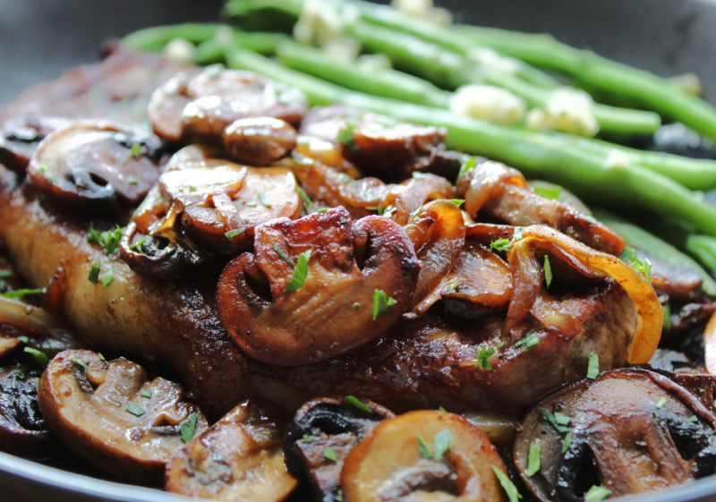 closeup of steak with caramelized onions and mushrooms