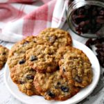 white plate of cookies with jar of raisins in the background