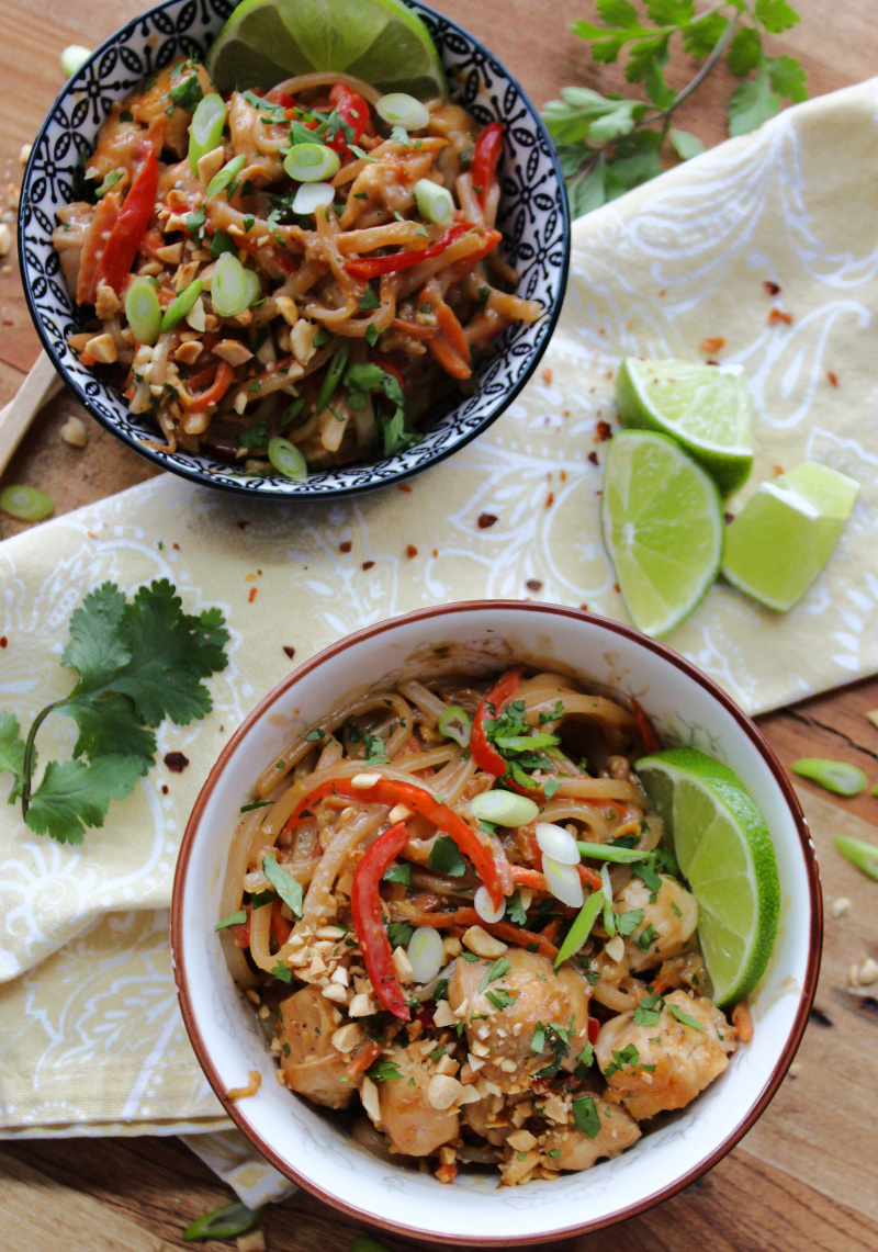 two bowls of spicy chicken pad thai garnished with lime wedges