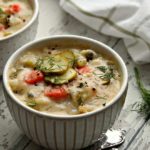 bowl of dill pickle soup garnished with sliced pickles